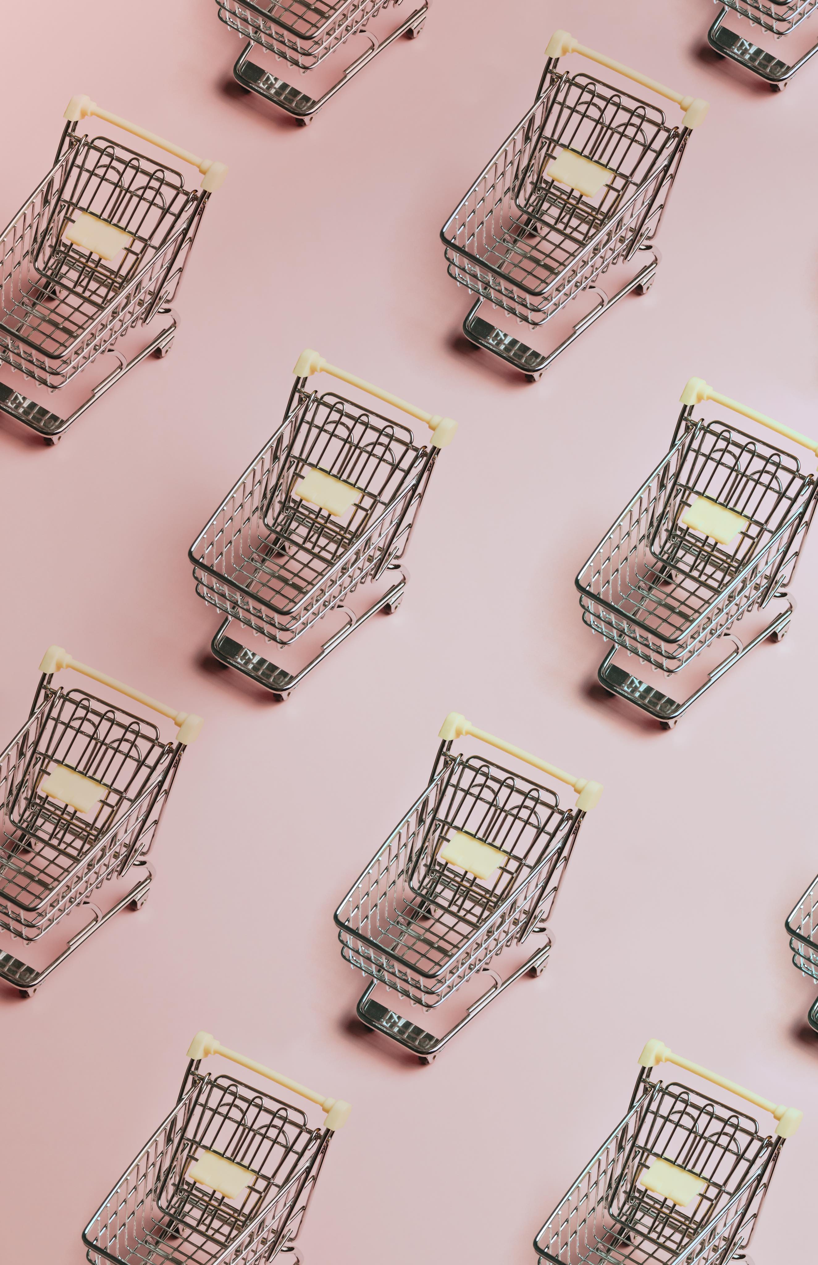 grid of shopping carts in a pink background